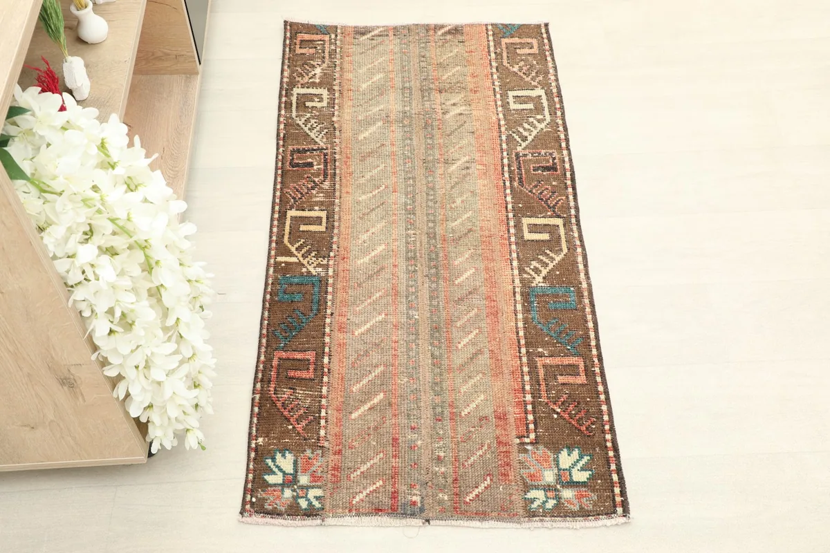 Overhead view of the vintage brown and beige rug, showing its full length and width with tribal motifs.