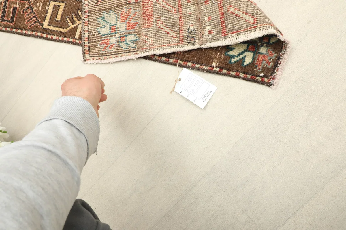 A hand next to the rug, showing its scale and the texture of the hand-knotted wool pile.