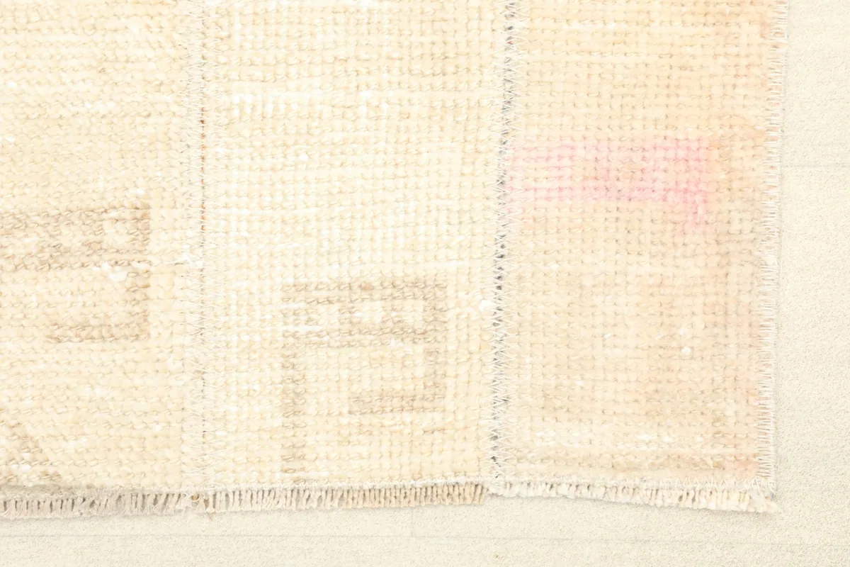 Close-up of the rug's surface, highlighting the subtle geometric motifs and faint rose discoloration.