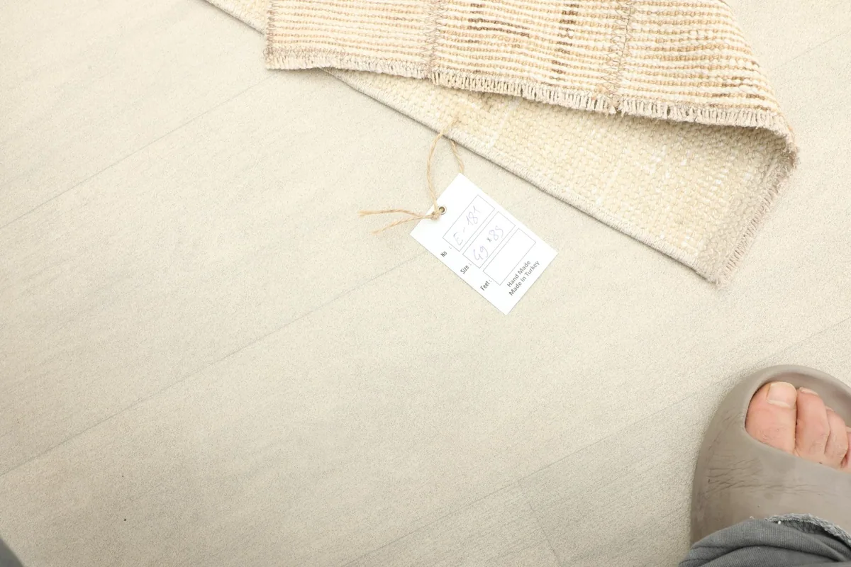Image showing the rug's label with size and material details, next to a foot for scale.