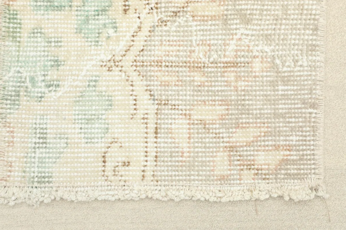 Close-up detail of the rug's edge, showing the hand-knotted texture and muted colors.