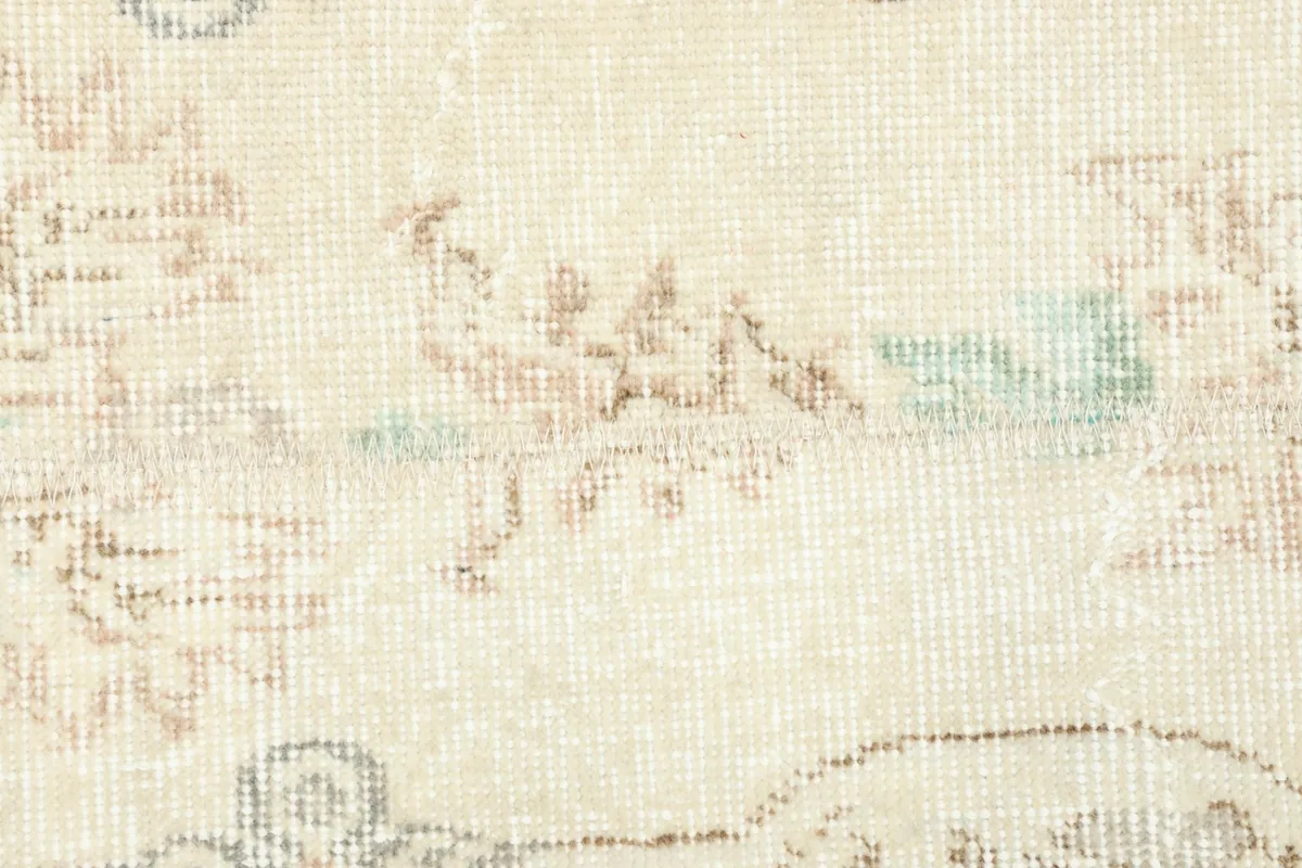 Detailed view of the rug's wool pile and the intricate, faded floral motifs.