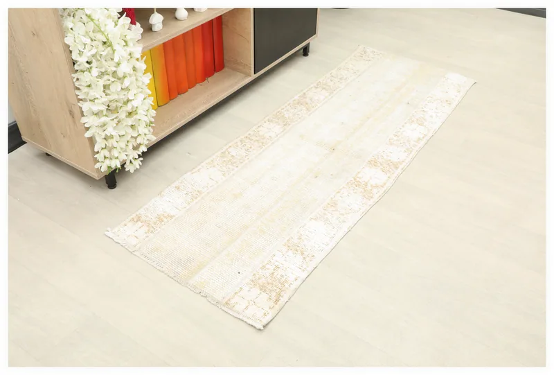 Full overhead view of the 2'0" x 5'6" ivory and tan distressed vintage runner rug on a light floor.