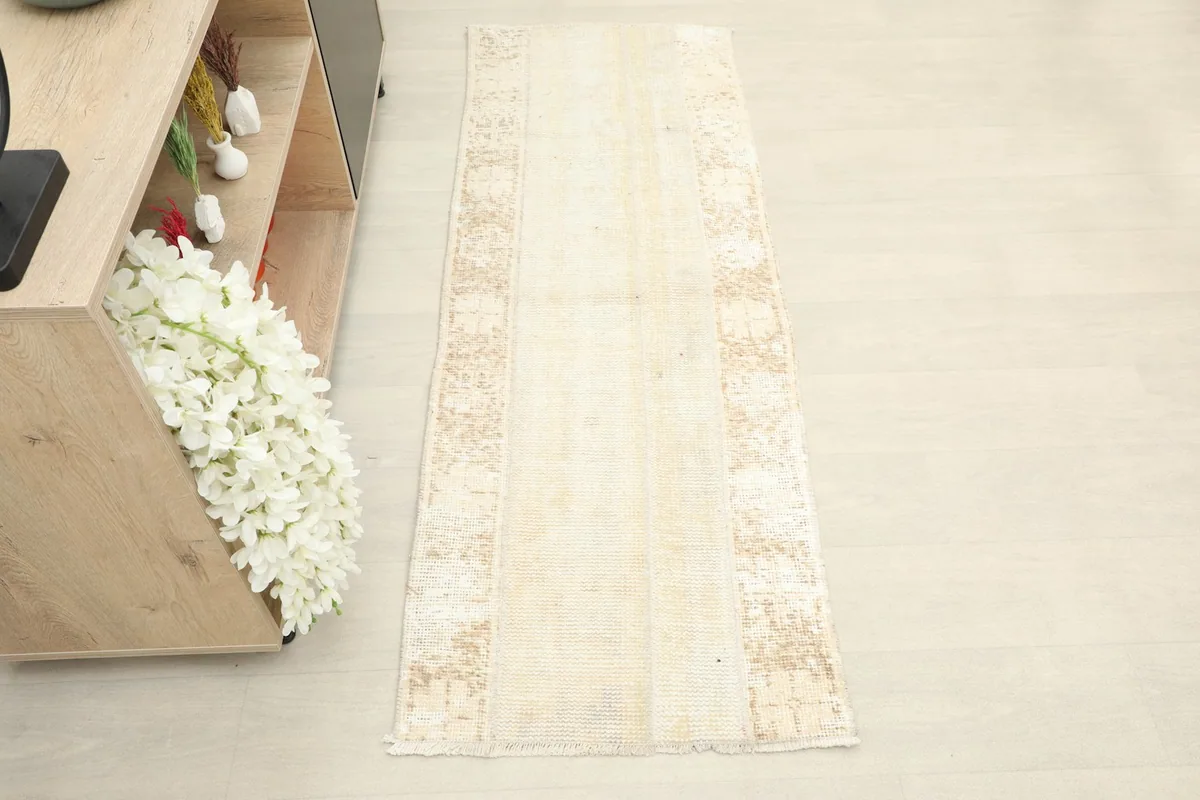 Overhead view of the ivory and tan vintage runner rug, showing its full length and distressed patterns.