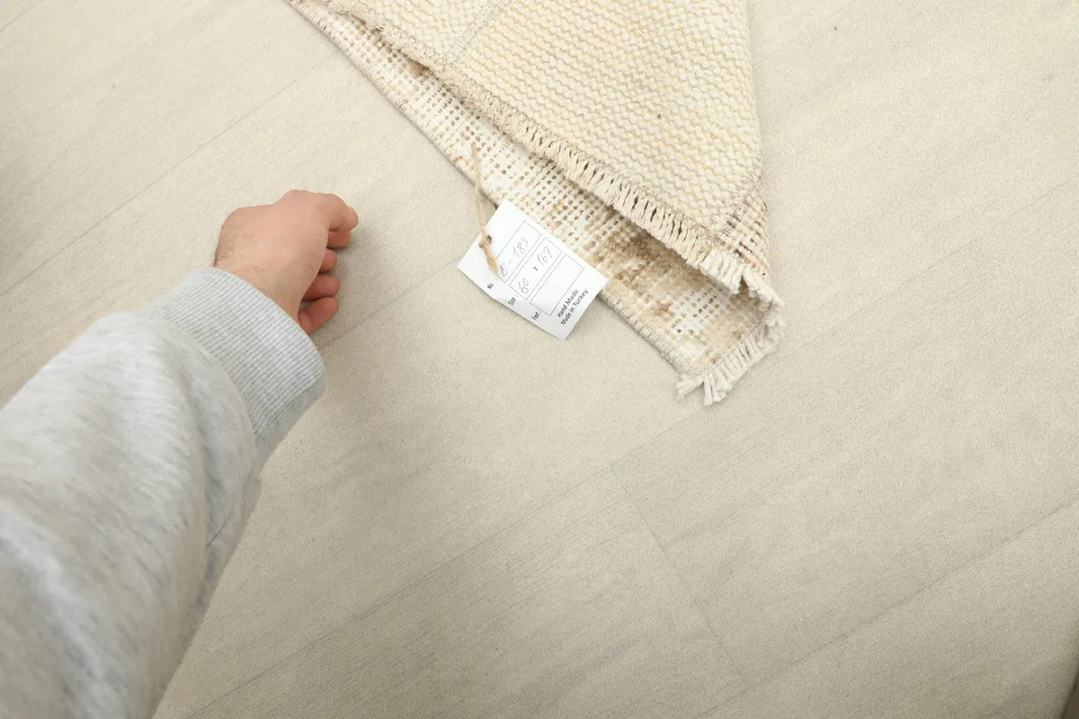 Hand pointing to the care label attached to the back of the vintage Anatolian runner rug.