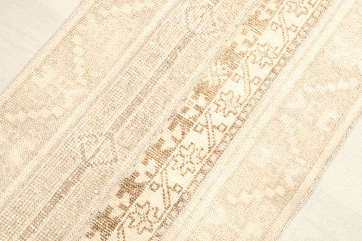 Angled view highlighting the distinct tan and beige striped motifs and textures of the rug.