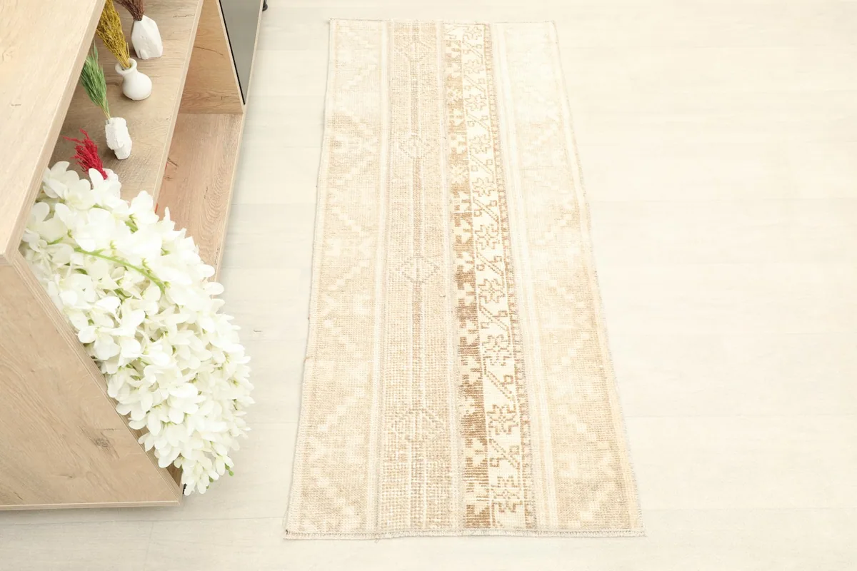 Overhead view of the tan and beige striped rug in a room setting next to a wooden shelf.