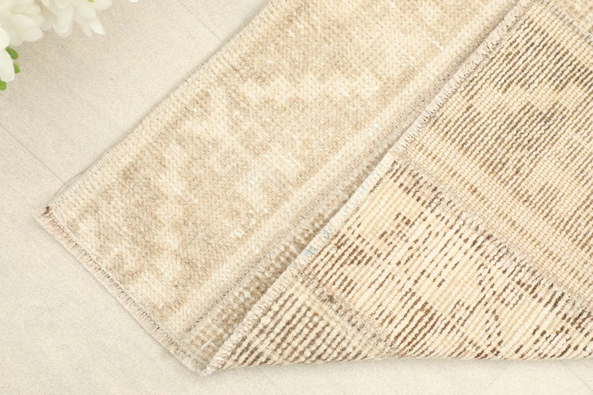 Corner of the rug folded to show the hand-knotted cotton foundation and the reverse side.
