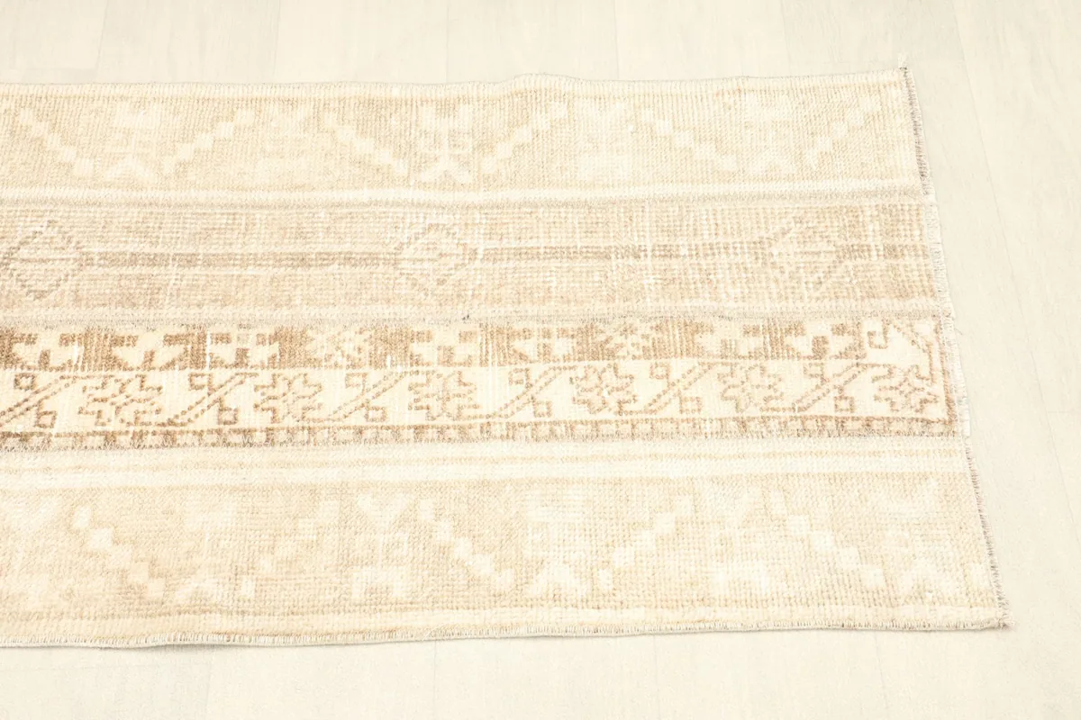 Overhead shot showing the full length and various striped patterns of the tan and beige rug.