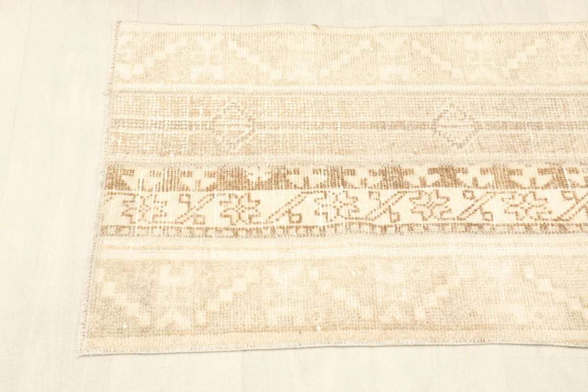 Overhead view of the rug's surface, emphasizing the blend of tan and beige colors and geometric motifs.
