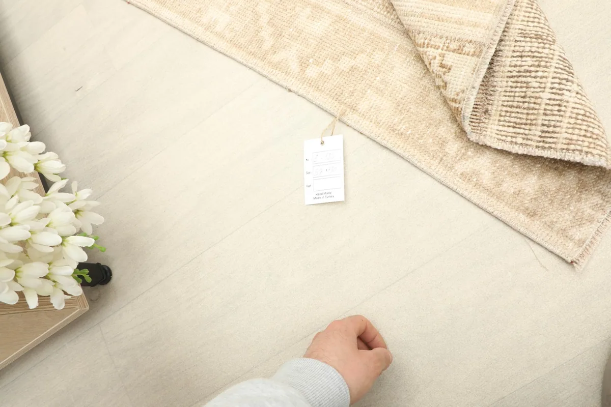 Overhead view with a hand near the rug, showing the scale and the product tag.