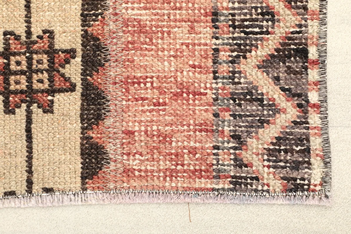 Close-up detail of the rug's edge, showing the rust and black colors and wool pile texture.