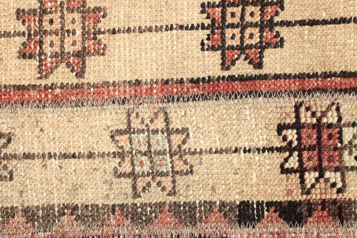 Macro shot of the beige stripe with black and rust geometric motifs and the wool pile.