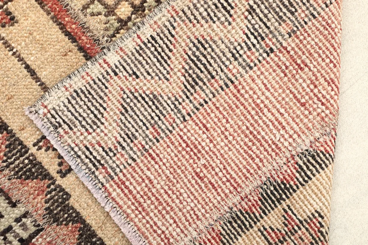 Folded corner showing the reverse side of the hand-knotted wool rug and its cotton foundation.