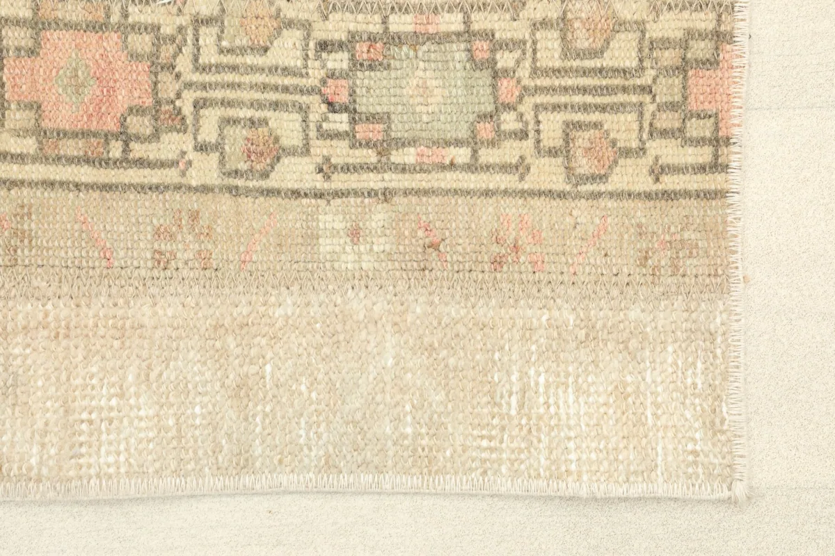 Close-up view of a beige stripe with subtle texture and faded rose patterns near the rug's edge.