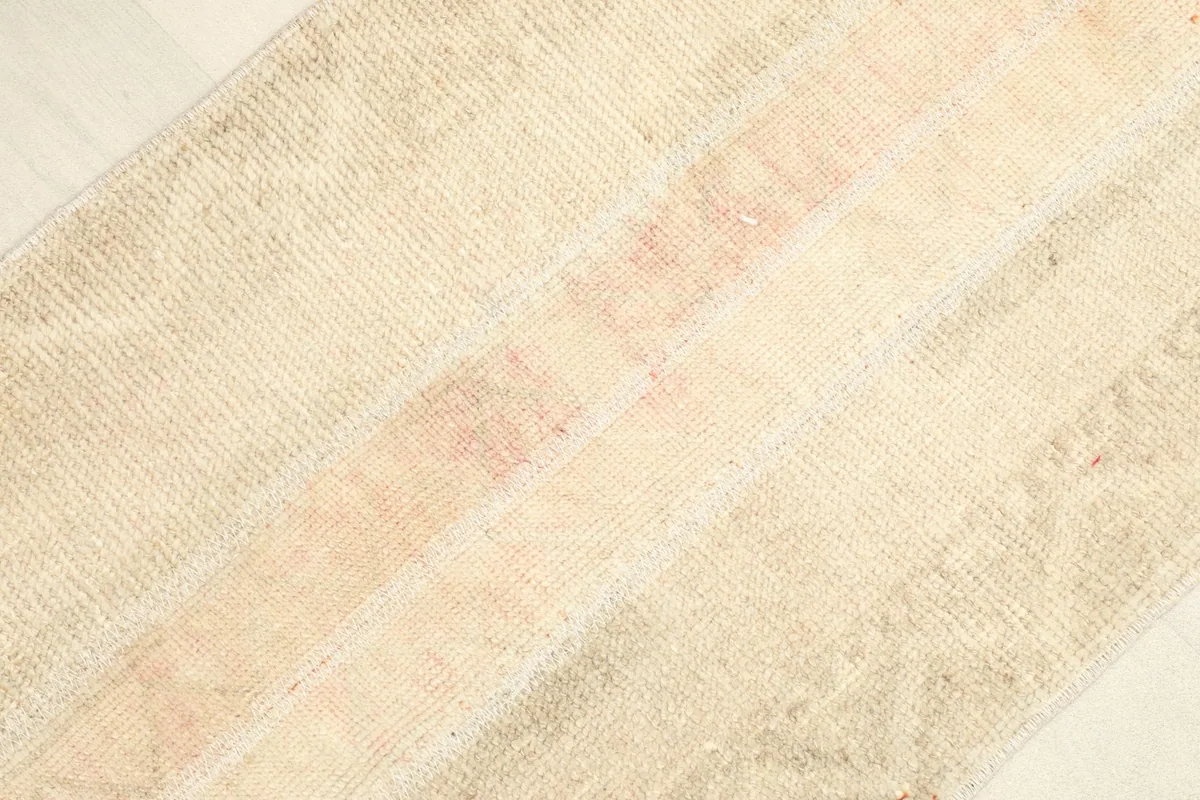 Angled close-up of the rug's surface, emphasizing the faded rose and beige tones.