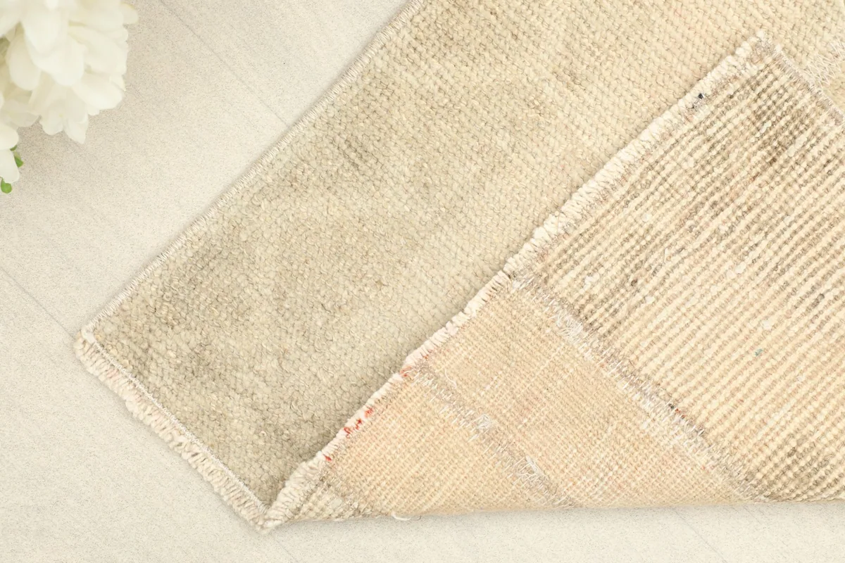 Corner of the rug folded back, revealing the hand-knotted cotton foundation and wool pile.