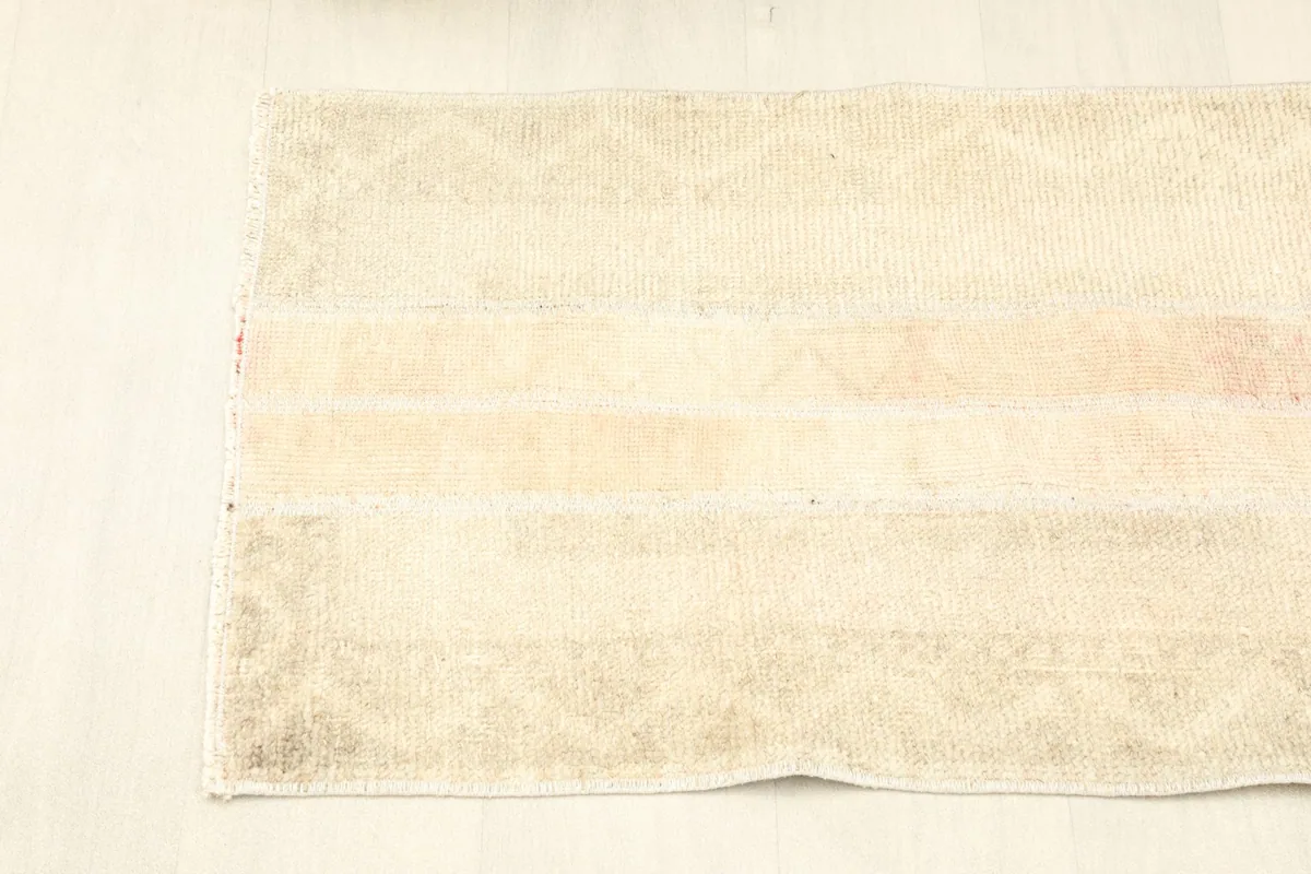 Overhead view of the rug's short end, showing the faint geometric patterns and color variations.