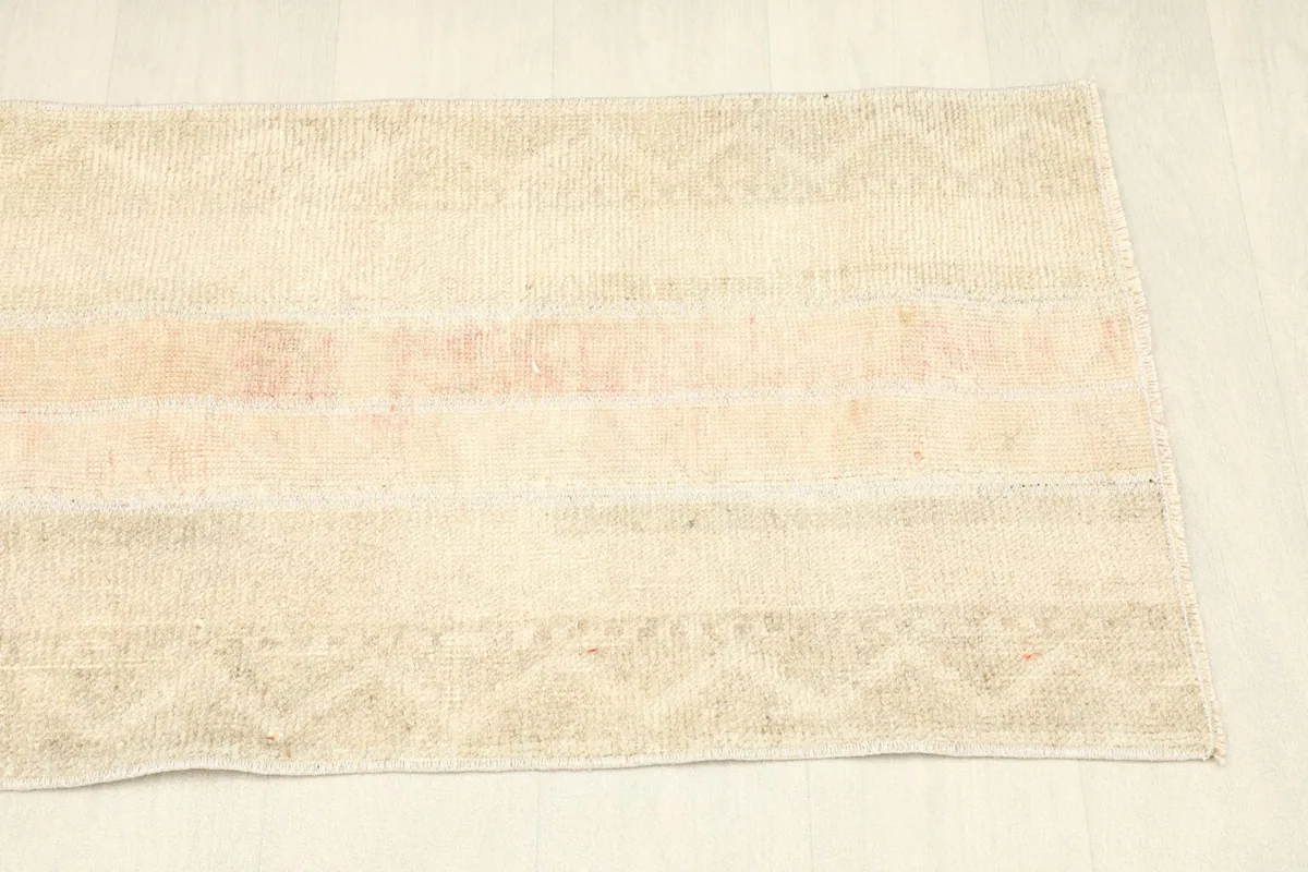 Overhead view of the rug's long side, highlighting the subtle rose and beige color bands.