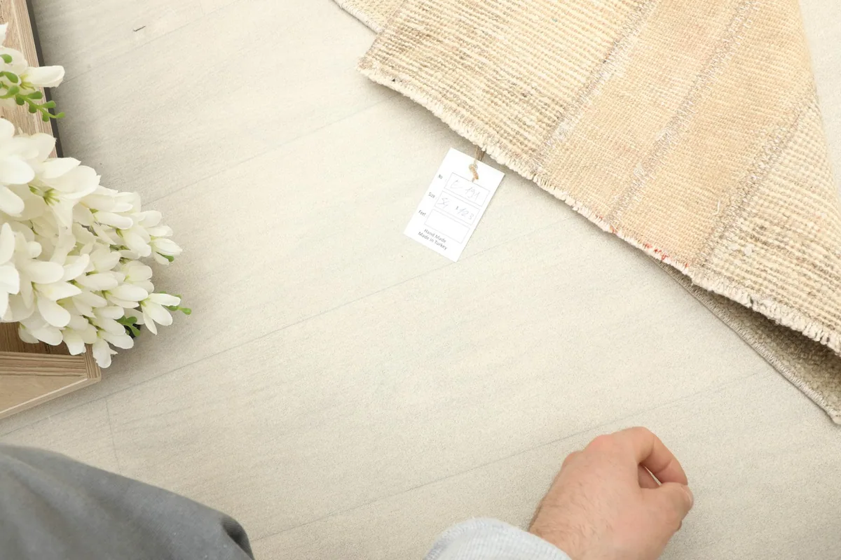 Close-up of the rug's texture next to a hand, providing a sense of scale and material.