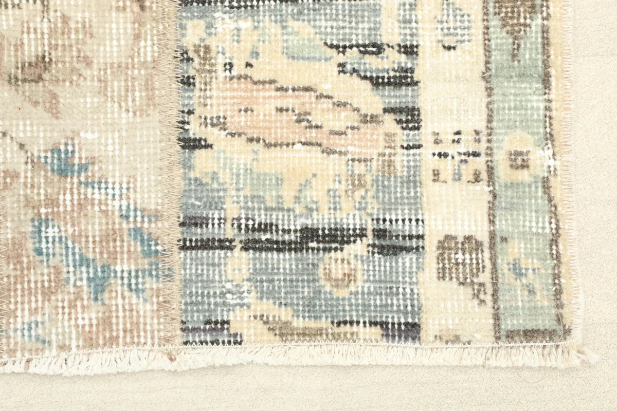 Close-up detail of the rug's texture, showing individual patchwork sections and muted colors.