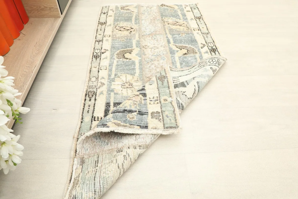 Rug folded at an angle, illustrating the flexibility and thickness of the vintage wool pile.