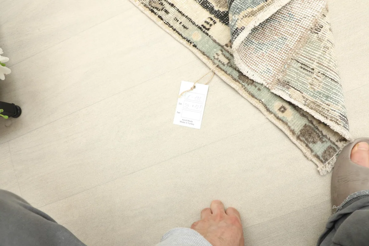 Perspective shot from above, including feet for scale and a product tag near the rug.