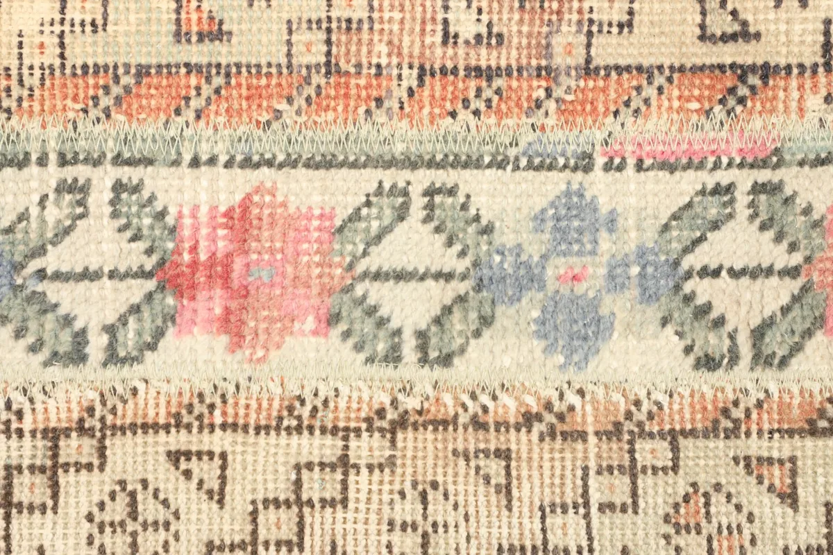 Detailed view of the hand-knotted pile and the intricate rose and blue floral motifs within a stripe.