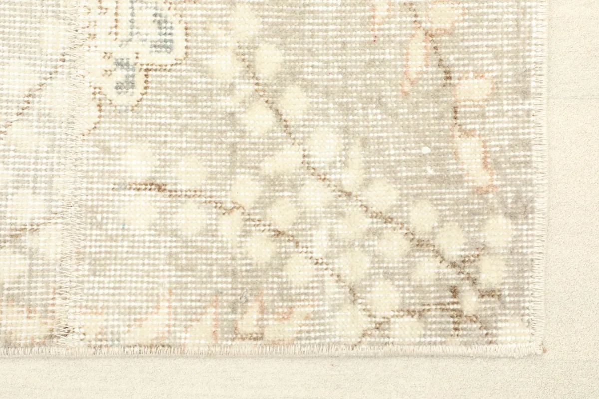 Close-up of the rug's corner, showing the subtle distressed texture and beige-gray tones.