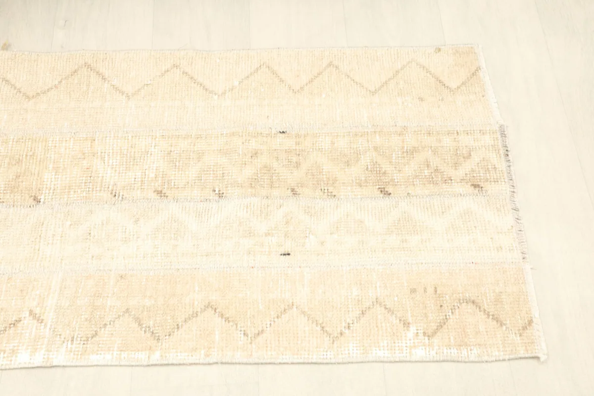 Side angle view of the rug, emphasizing its rectangular shape and the light beige color.