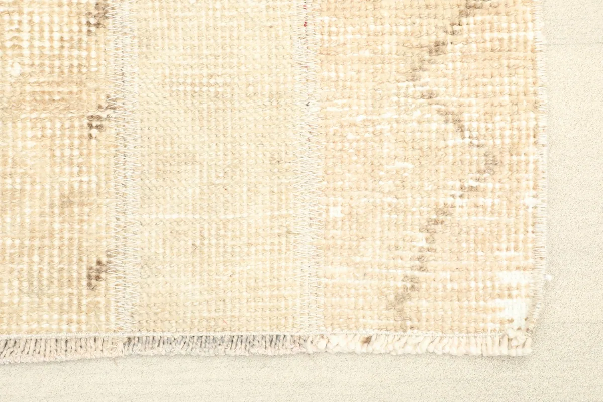 Close-up detail of the rug's beige and tan geometric pattern and low pile texture.