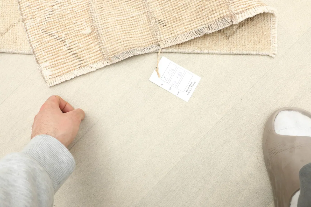 A person's hand next to the rug and product tag, indicating its small size.