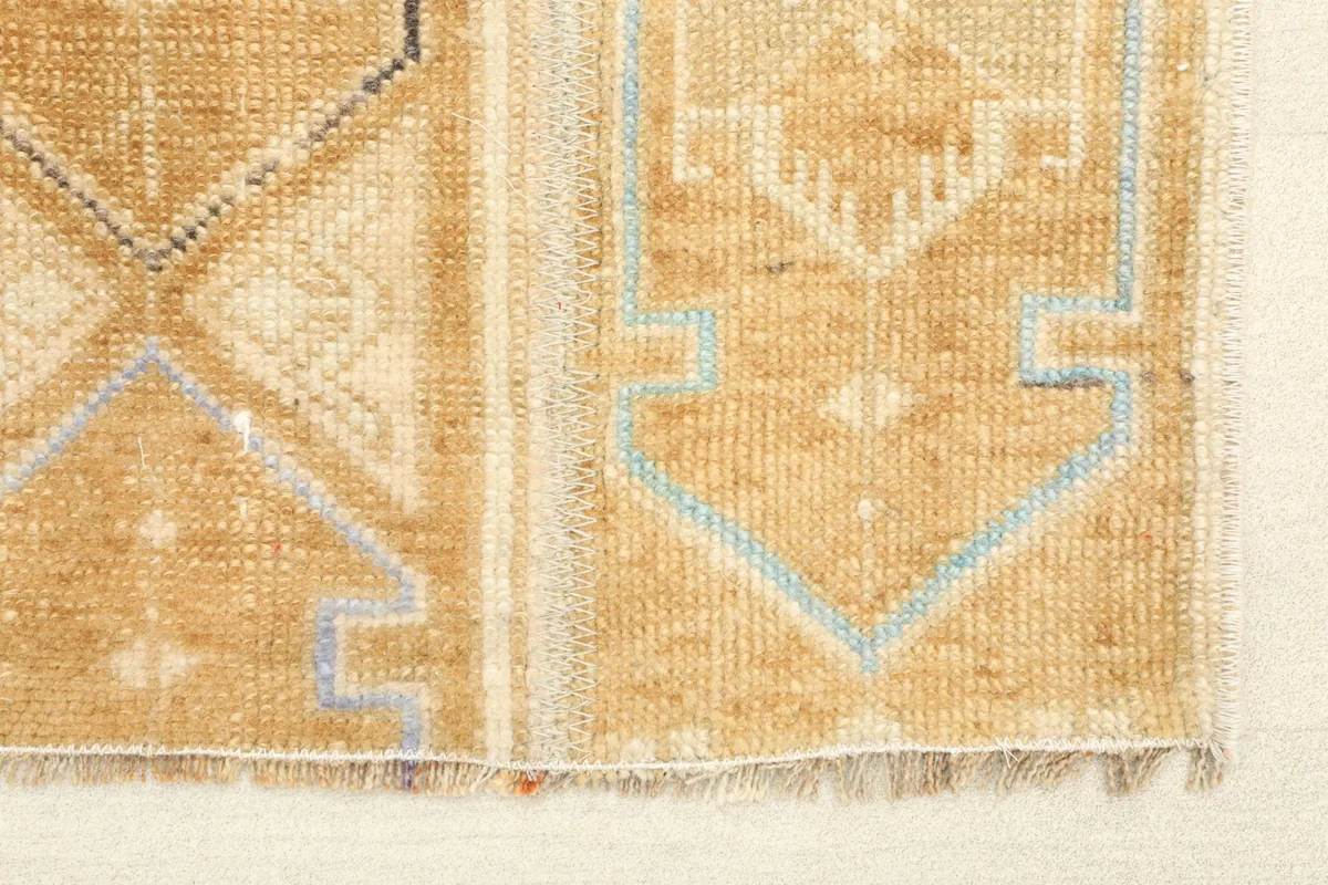 Close-up of the low pile and geometric patterns in tan, beige, and blue