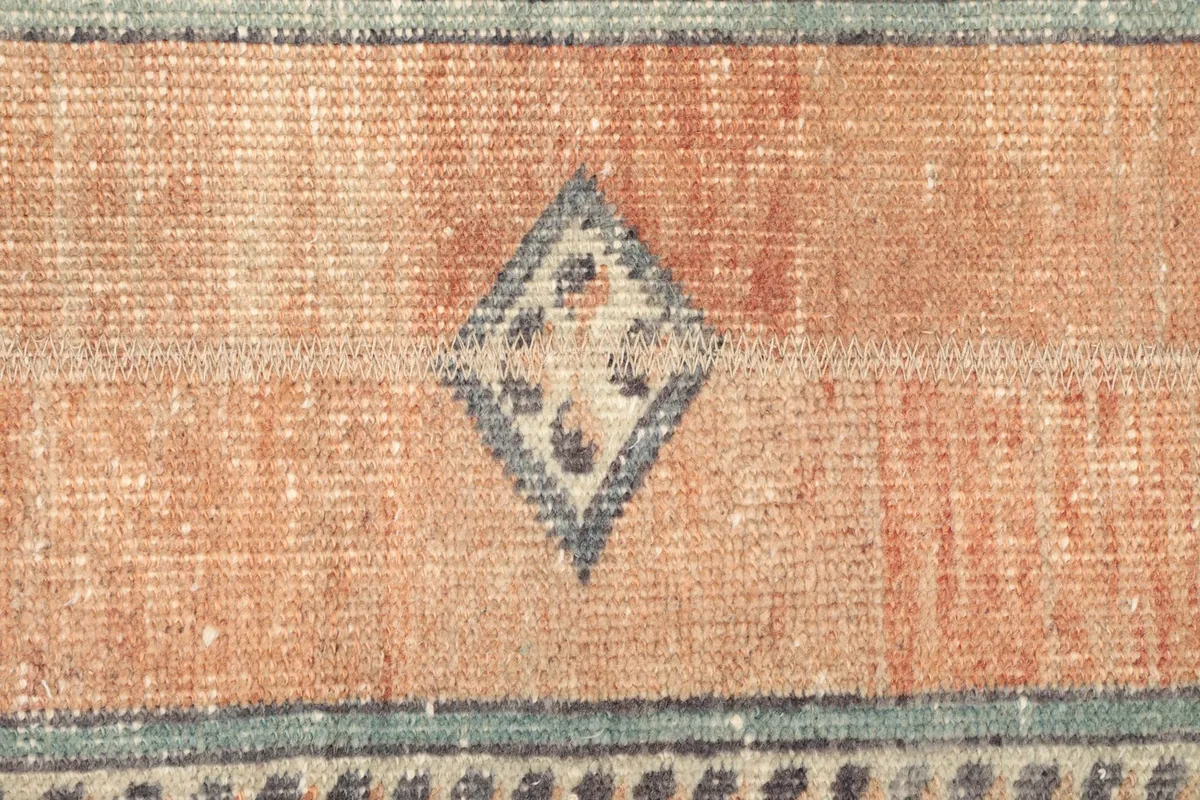 Close-up view of the low wool pile and a central geometric design on the orange field.