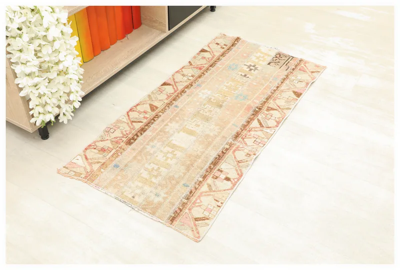 Full top view of the beige, brown, and pink tribal area rug on a white background.