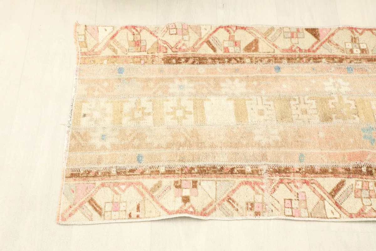 View of one side of the rug, showing the distinct border design in brown and pink.