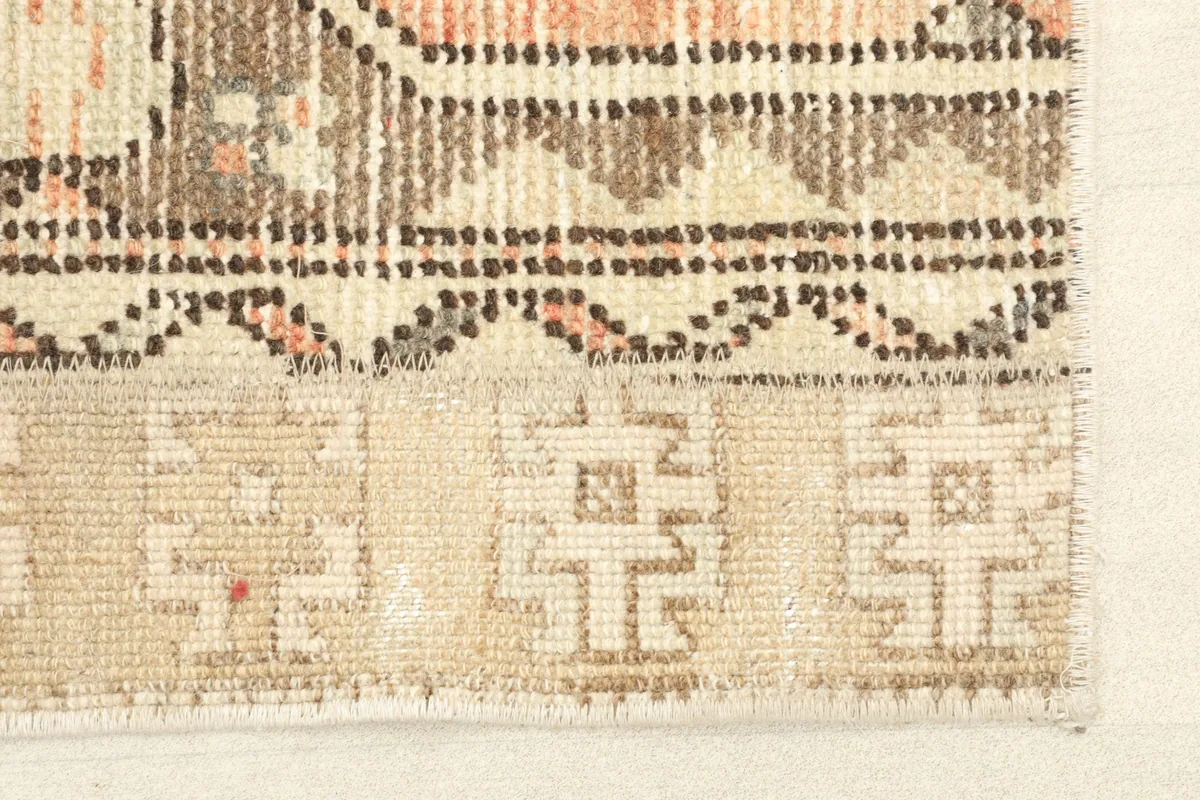 Close-up detail of a beige section with geometric motifs and a brown patterned strip.