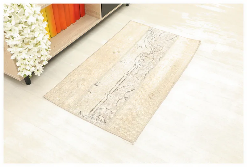 Full top view of the beige and gray vintage Anatolian rug on a white floor.