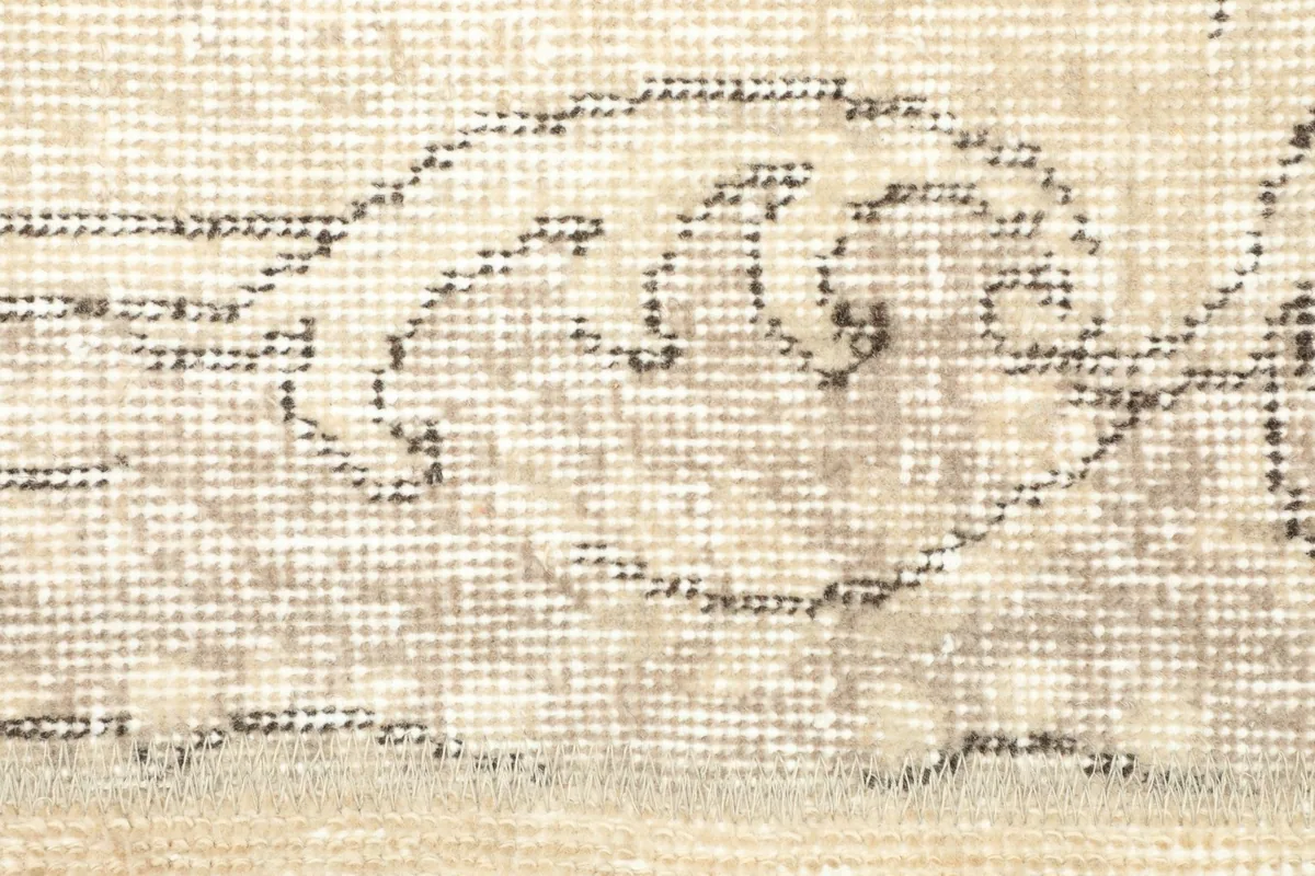Close view of the low wool pile and the intricate, faded gray knotting of the design.