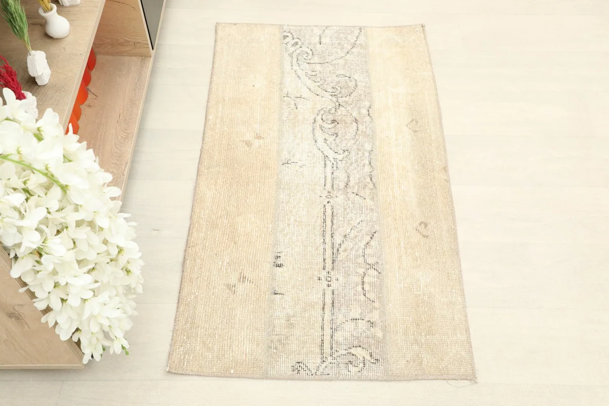Overhead view of the small beige vintage rug, showcasing its central gray abstract pattern.