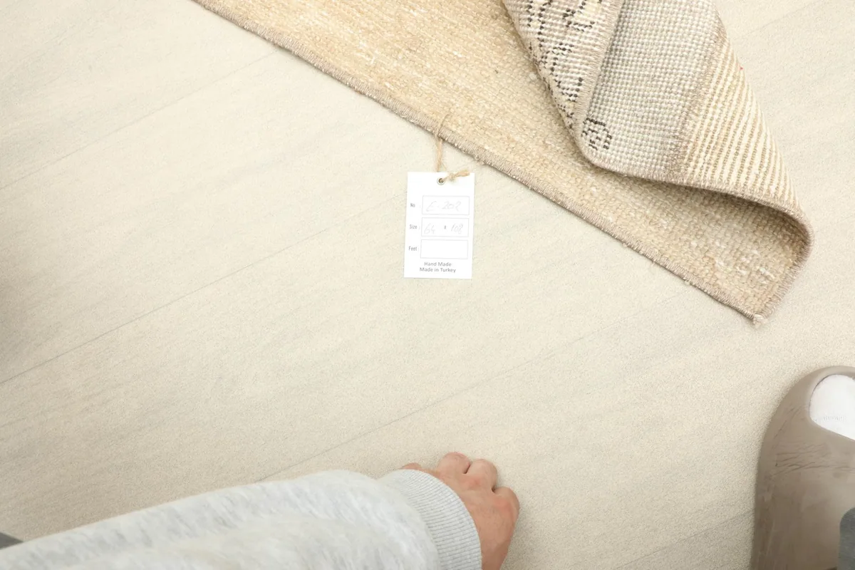 Overhead view with a hand and foot for scale, showing the rug's size and texture on the floor.