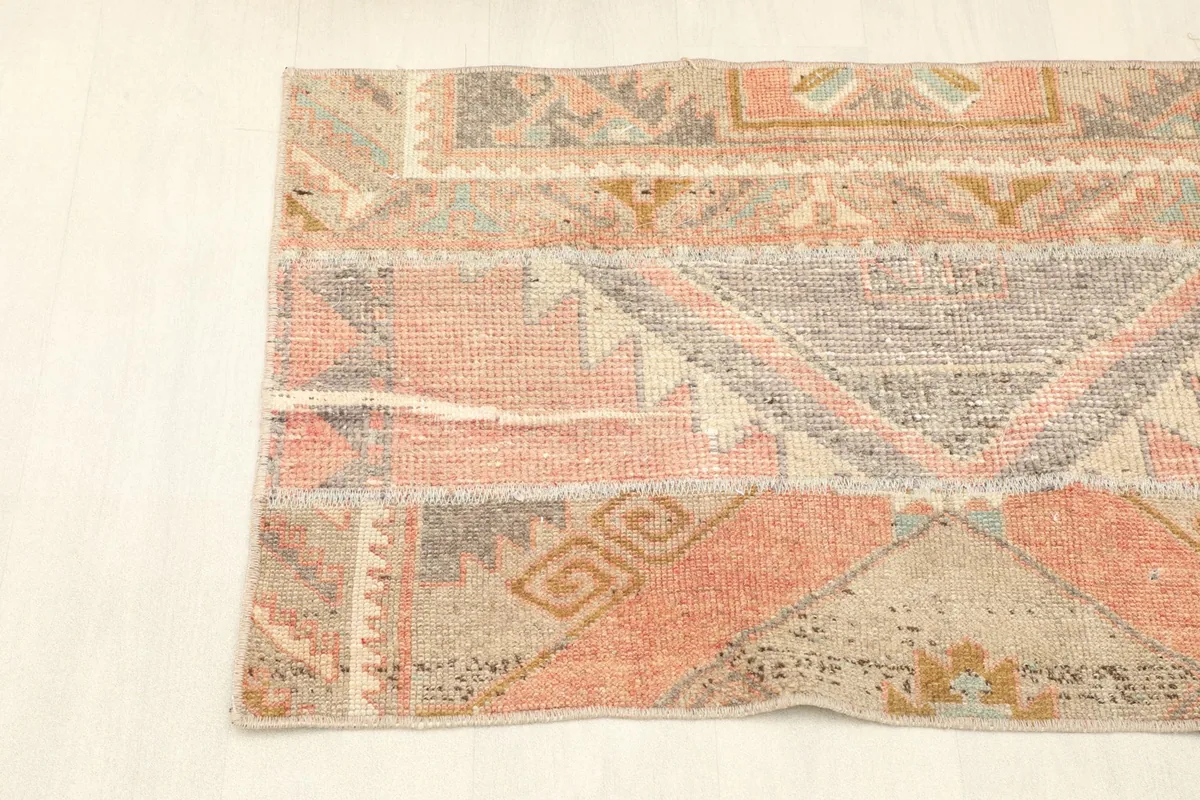 Angled shot of the runner rug, focusing on the left half and the blend of rose, beige, and gray tones.