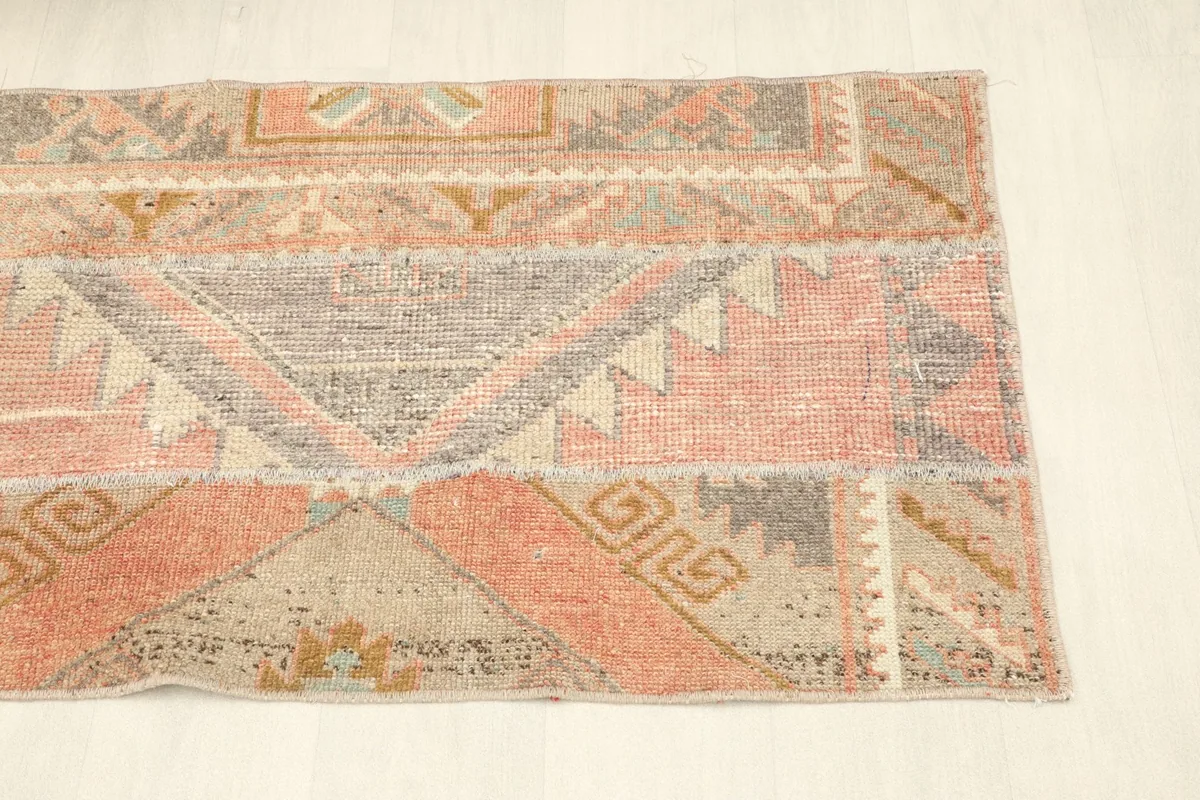 Angled shot of the runner rug, focusing on the right half and the blend of rose, beige, and gray tones.