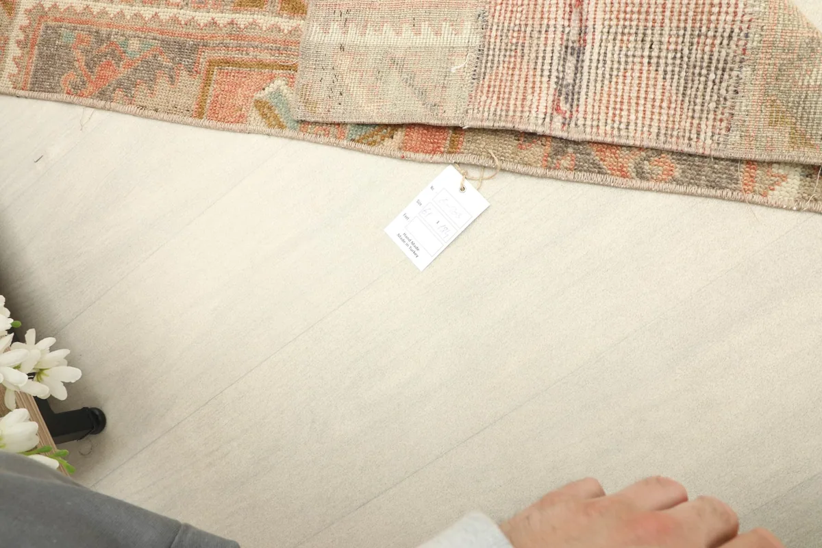 Context shot showing a corner of the rug with a small product tag, indicating its authenticity.