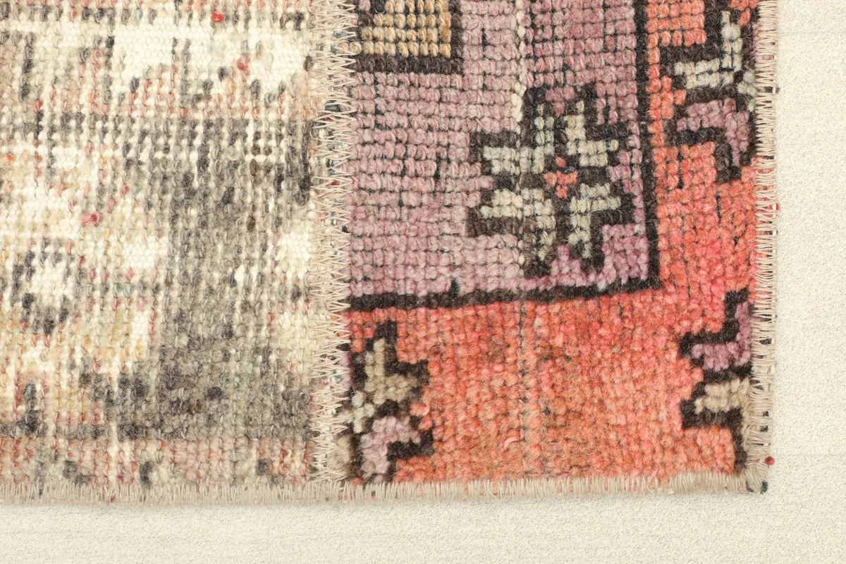 Close-up detail of the rug's edge, showing the texture and some of the orange and pink tones.