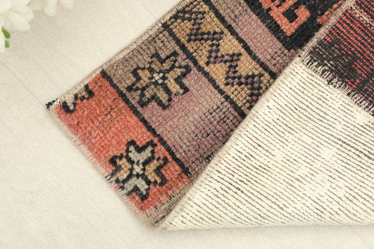 Corner of the rug folded to reveal the cotton foundation and the reverse side of the knotting.