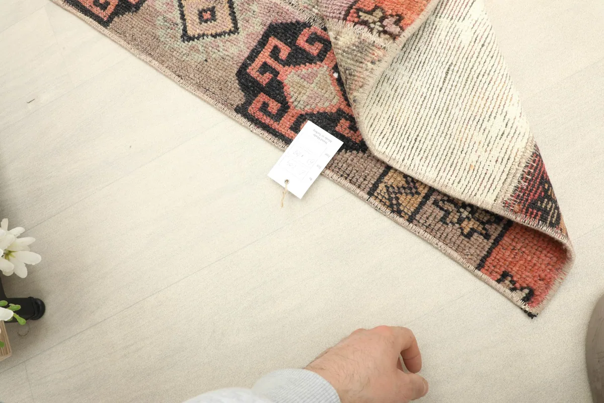 Hand reaching towards the rug, indicating its mini size and providing a sense of scale.