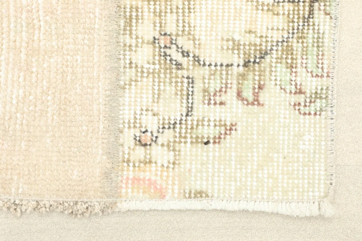 Close-up detail of one panel of the rug, showing faded floral motifs and the low wool pile.