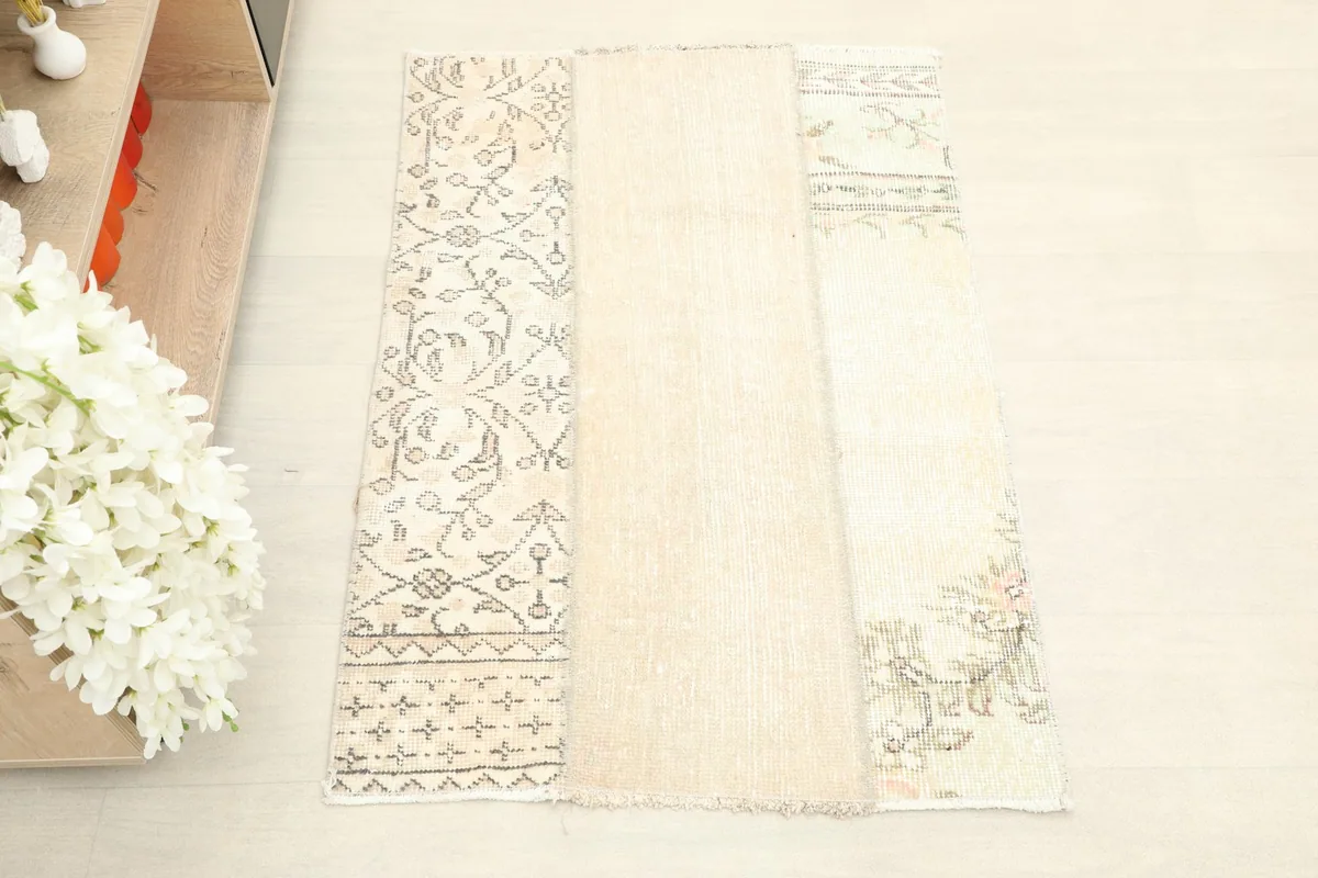 Overhead view of the beige patchwork rug, highlighting the varied patterns and color tones.