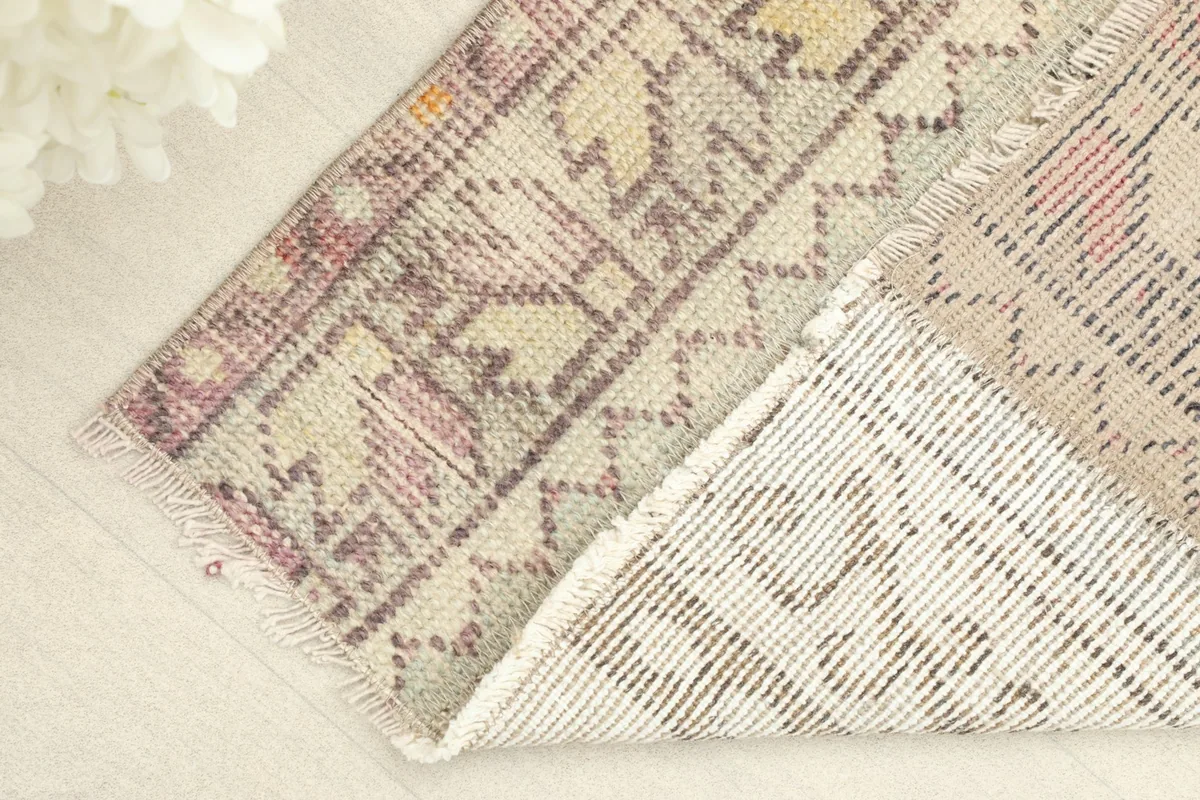View of the rug's back and a folded corner, showing the cotton foundation and knotting